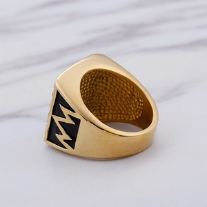 Makro-Seitenansicht eines Gold-Titan-Hip-Hop-Rings mit schwarzen Emaille-Blitzmustern