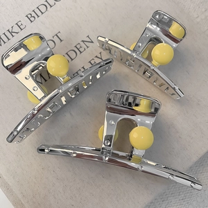 Detail of silver metal shark hair clips with yellow pearls on a minimalist book