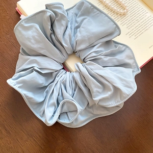 Vue détaillée d'un chouchou en tissu bleu clair avec texture mate et bords volantés