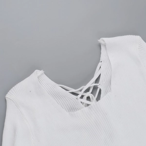 Detail of white knit dress featuring a cross-tie neckline and vertical ribbed texture