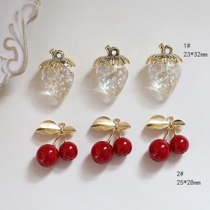 Detailed view of DIY strawberry and cherry fruit pendants with golden leaves for jewelry