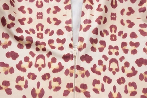 Close-up detail of smooth leopard print fabric and metallic front zipper closure