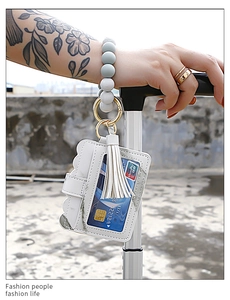 Detail of silicone bead wristlet with white leather card holder held by a traveler