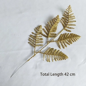 Detailed view of a 42cm golden artificial glitter fern branch for festive decoration