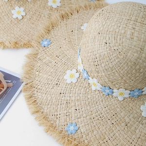 Summer raffia straw sun hat for women with knit daisy appliques and raw fringe edges