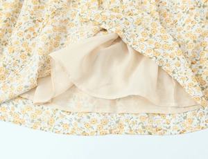 Détail de l'ourlet de robe à fleurs jaunes avec doublure beige en mousseline légère