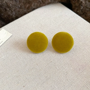 Detail of round mustard yellow velvet button earrings with soft fabric texture