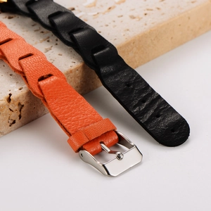 Macro shot of orange and black braided leather bracelets with silver metal buckles