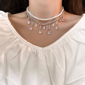 Détails d'un élégant collier double rang avec perles blanches et pompons en zircons brillants