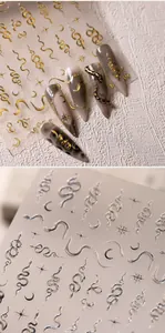 Macro detail of metallic gold snake and moon nail stickers applied on marble nails