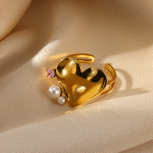Golden heart-shaped ring with elegant pearls and pink gemstone on beige silk background