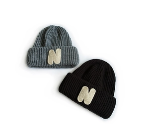 Detail of grey and black knitted beanies with N letter patch and textured fabric