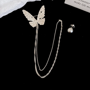 Macro shot of butterfly chain brooch with hammered metal texture and dark grey pearl