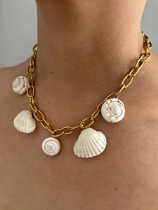 Detail of gold chain necklace featuring white shell pendants on a model's neck