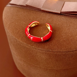 Macro shot of red enamel bamboo joint ring with gold plating on a brown velvet box