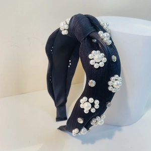 Detailansicht des schwarzen Knotenstirnbandes mit weißen Perlen und funkelnden Strassblumen