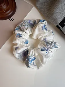Close-up of white satin scrunchie with intricate blue and purple floral embroidery details