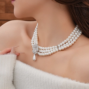 Close-up of elegant multi-layer pearl necklace with a rhinestone clover pendant on a model