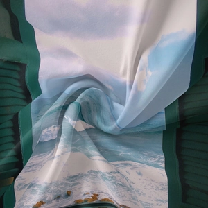 Close-up of lightweight chiffon fabric with blue ocean landscape print and green borders