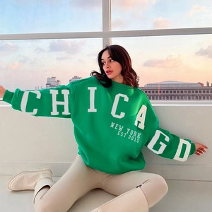 Gros plan d'un sweat vert oversize avec imprimé Chicago blanc sur un tissu en coton doux