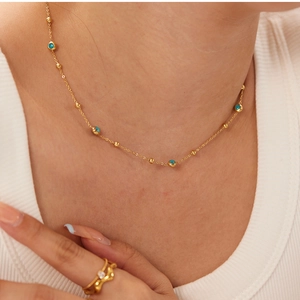 Detail of 18K gold plated necklace with blue evil eye beads worn by a model
