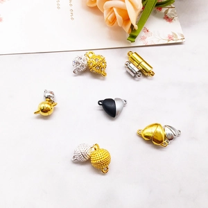 Strong magnetic jewelry clasps in heart and ball shapes on white marble background