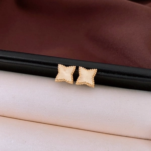Macro detail of gold star stud earrings featuring radial texture and beaded edge design