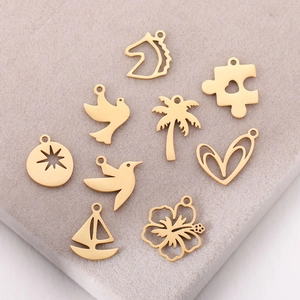 Macro detail of 10 gold stainless steel bird and plant pendants on velvet display