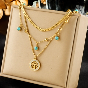 Gold multi-layer necklace with Tree of Life pendant and turquoise stones on display stand
