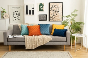 Velvet diamond quilted cushions with pom-pom trim in vibrant colors on a sofa