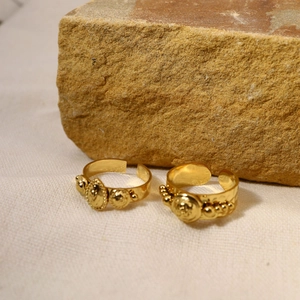 Detailed macro of vintage gold-plated rings with embossed medallions on textured stone
