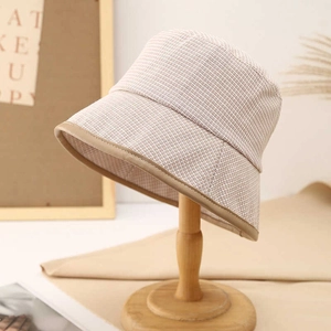 Beige plaid bucket hat with brown leather trim in a stylish 45-degree angle shot