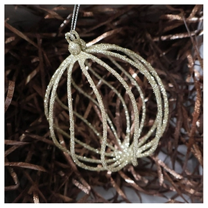 Macro shot of champagne gold hollow lantern ball ornament with glitter on festive background