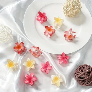 Candy-colored plumeria hair claws in pink and orange on silk background