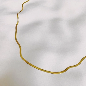 Macro shot of gold-plated stainless steel snake chain on white silk fabric background