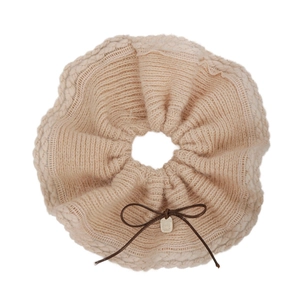 Soft beige knit scrunchie with brown bow and metallic charm detail for autumn hair styling