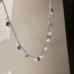 Detailed macro view of silver bead chain bracelet with purple zircon water drop charms