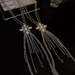 Close-up of gold and silver tassel body chains with pearl cross and crystal details