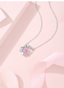 Close-up of silver crescent moon and star pendant with pink heart gemstone necklace
