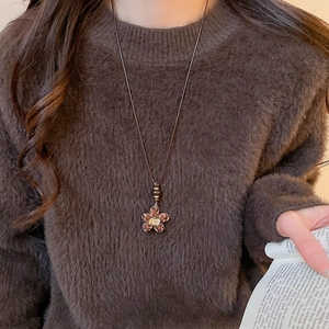Detail of leopard print flower heart pendant with crystal on brown sweater chain