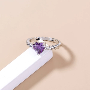 Detail shot of a silver twisted band ring featuring a purple heart-shaped zirconia gem