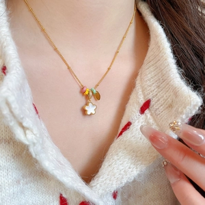 Detail of gold flower necklace with white petals and colorful beads on model neck