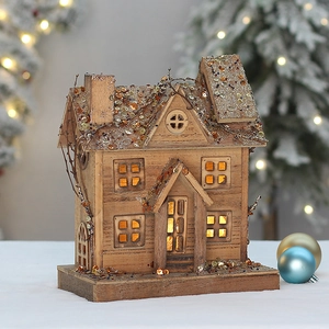 Lighted wooden Christmas house decoration with glowing windows and glittering snow roof