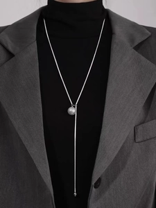 Y-shaped long pearl necklace with grey-purple pendant over a professional grey blazer