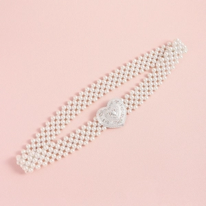 Close-up of pearl waist belt with a silver heart buckle featuring intricate carvings