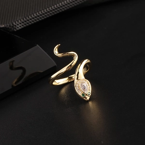Close-up of golden snake ring featuring clear teardrop zircon and green gemstone eyes
