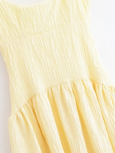 Detail shot of pale yellow dress showing the unique tree bark pleated fabric texture
