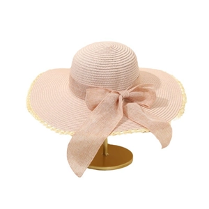 Women's pink wide brim straw sun hat with large bow and scalloped trim on gold stand