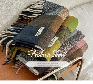 Close-up of multicolored plaid scarves with fringes and woven brand labels on wood