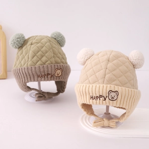 Detail von Baby-Wintermützen mit Steppmuster, zwei Bommeln und Bären-Stickerei